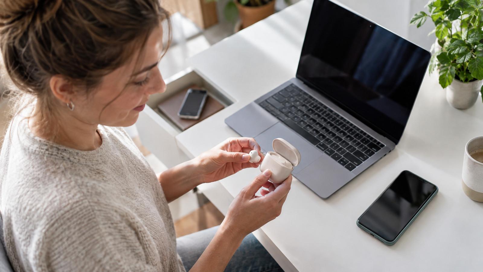 Kabellose Kopfhörer neben Smartphone und Laptop auf einem Tisch beim Koppeln